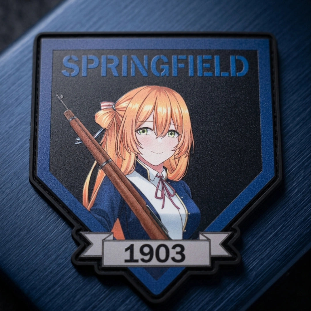 A shield-shaped embroidered patch featuring an anime-style character with orange hair holding a rifle, with the text 'SPRINGFIELD' at the top and '1903' on a banner at the bottom, displayed on a dark blue textured background.
