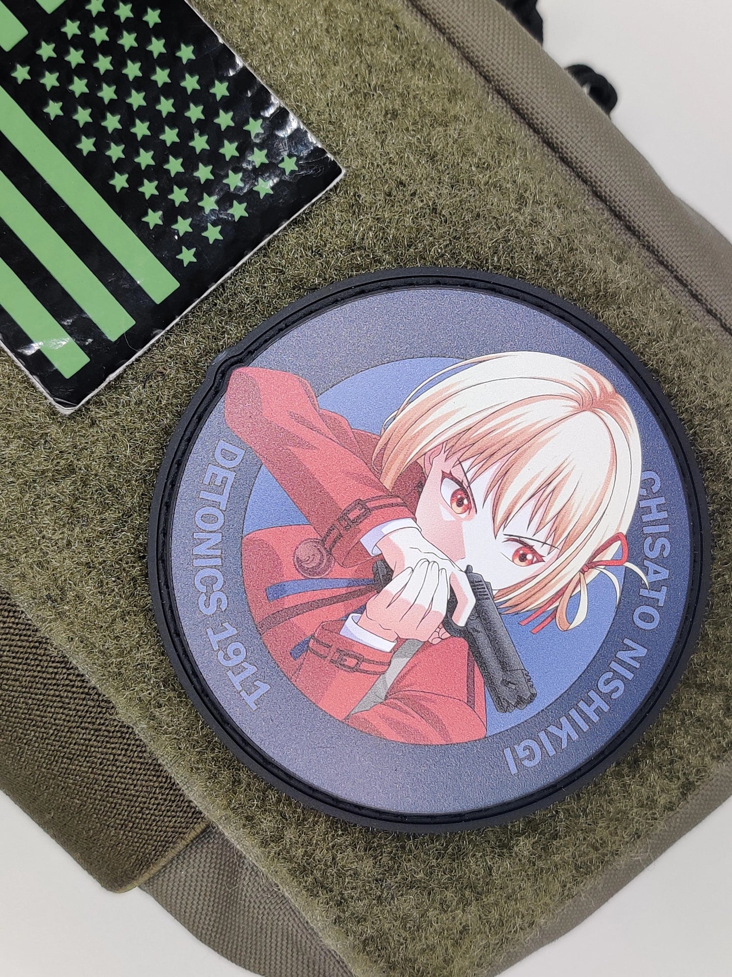 Circular patch with Chisato Nishikigi from the Anime Lycoris Recoil on a green fabric background