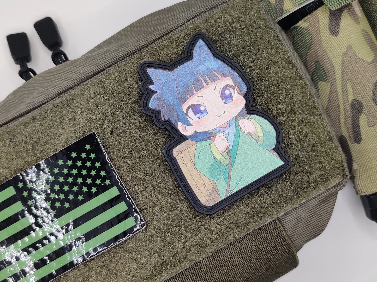 Patch of a character with blue hair and green outfit on a green bag with American flag patch.