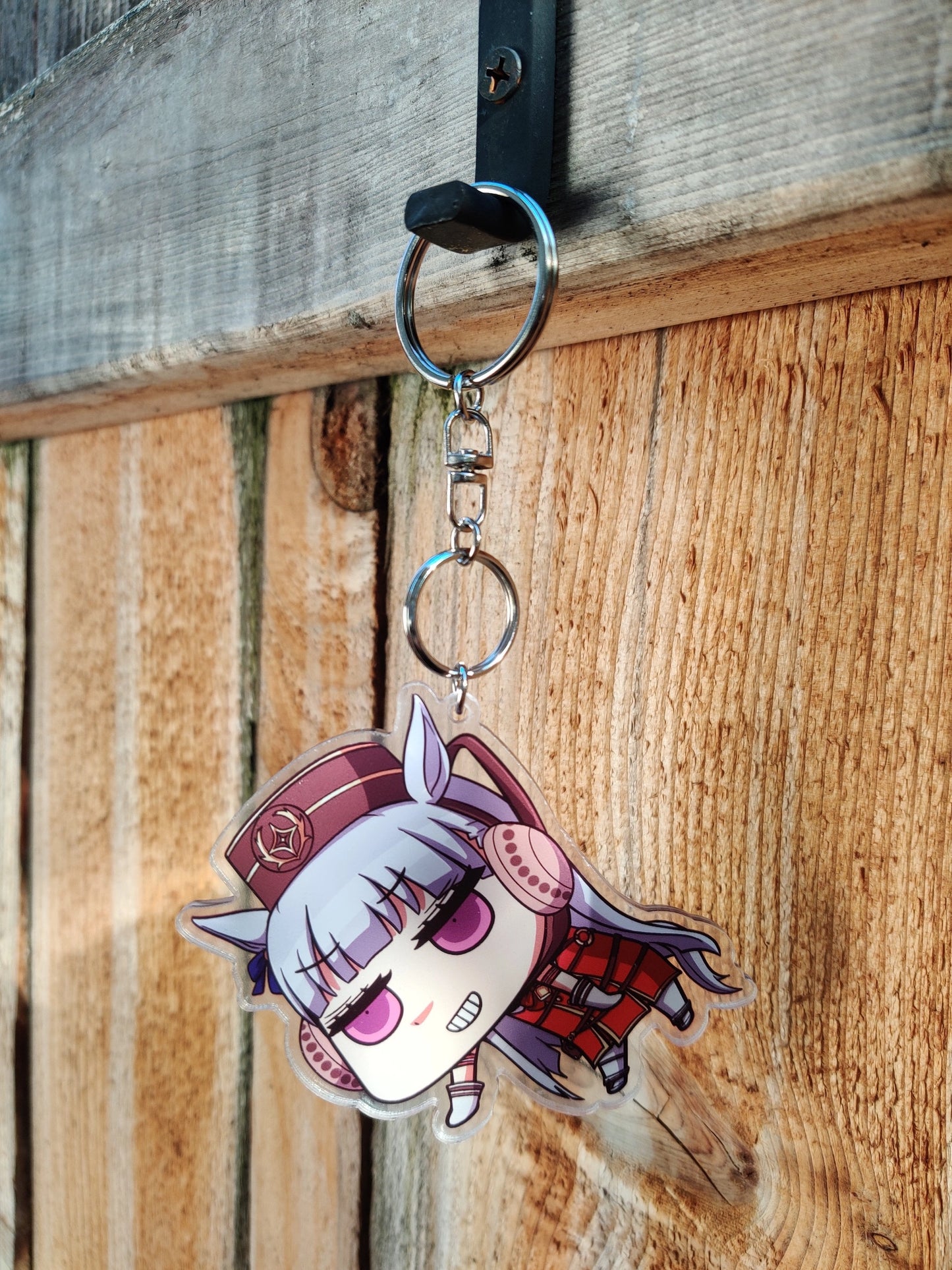 Keychain with Gold Ship from Uma Musume design on a wooden background