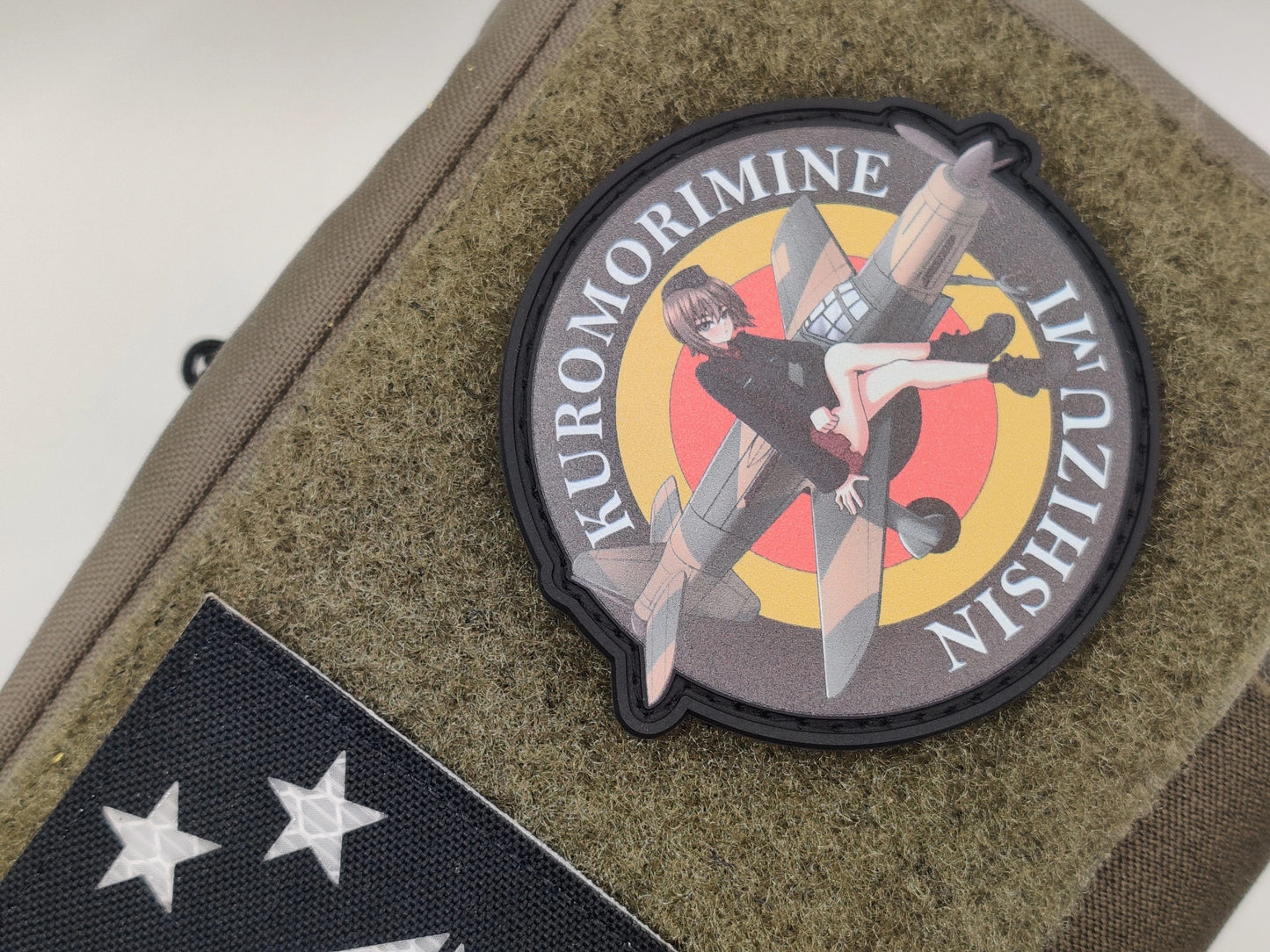Circular patch with Maho_Nishizumi sitting on a german airplane and text 'Kuromorimine Nishizumi' on a green texture background