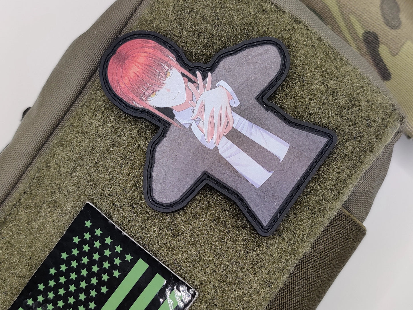 Patch of Makima from Chainsaw Man Anime with red hair and suit and tie clothing on a green fabric background