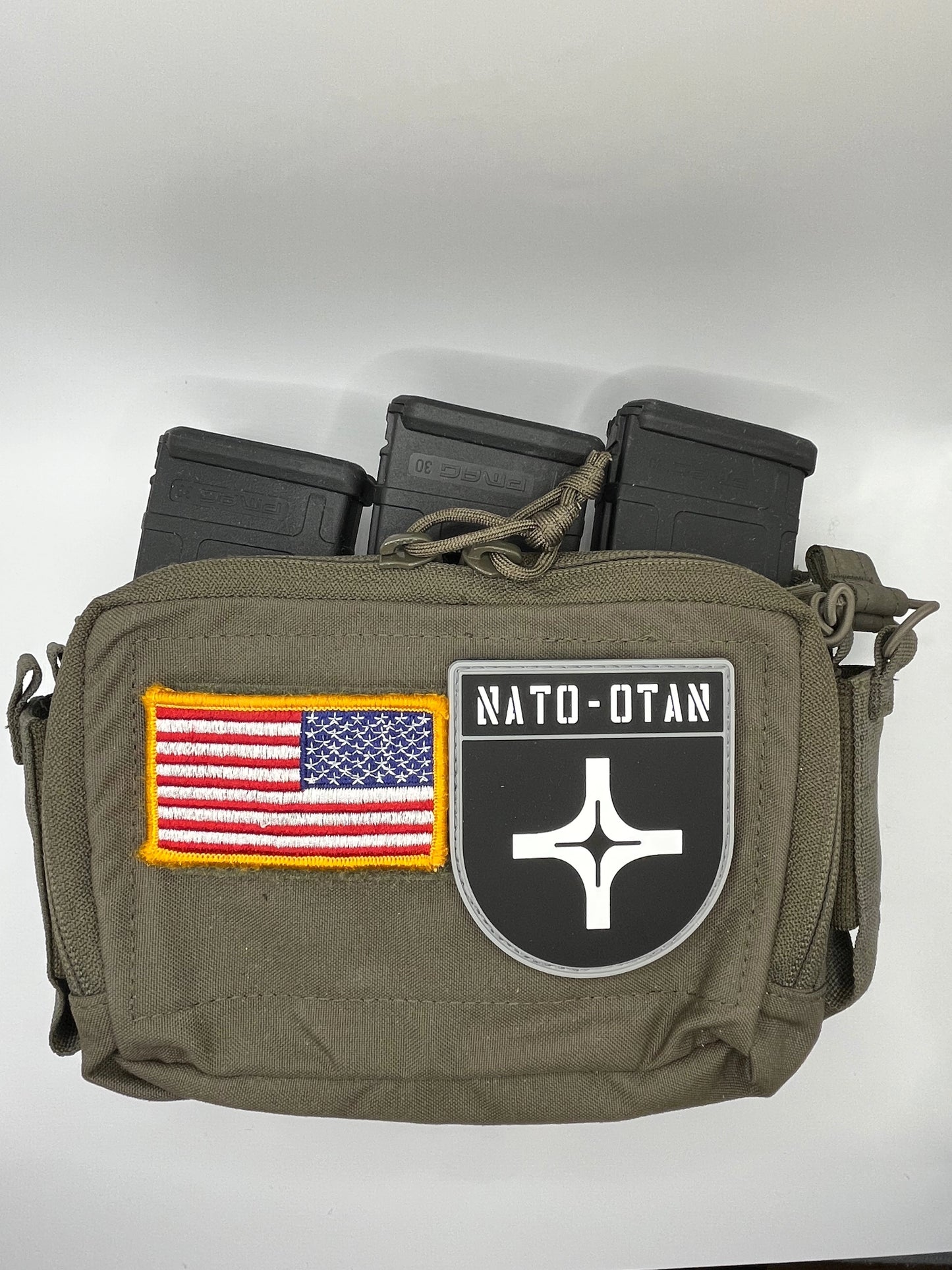 Olive green tactical pouch with American flag and NATO-OTAN patch on a white background