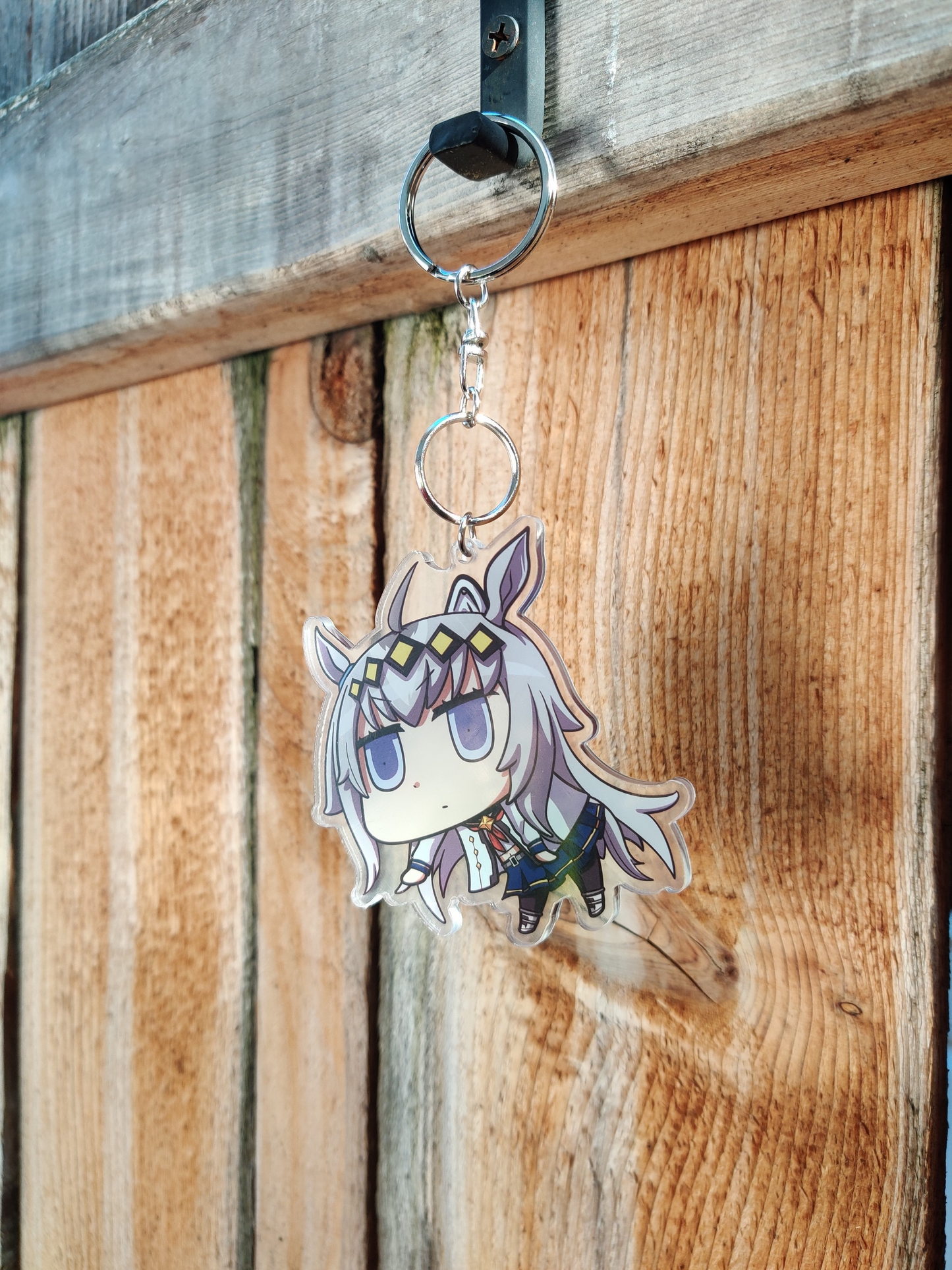 Anime character Oguri Cap from Uma Musume with silver hair and purple eyes on a wooden background