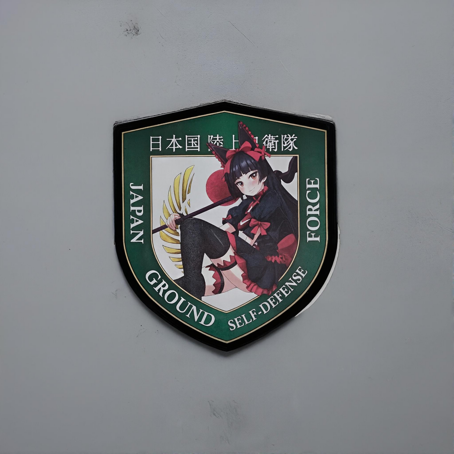 Emblem of Japan Ground Self-Defense Force with an anime-style Rory Mercury from the anime gate on a gray background