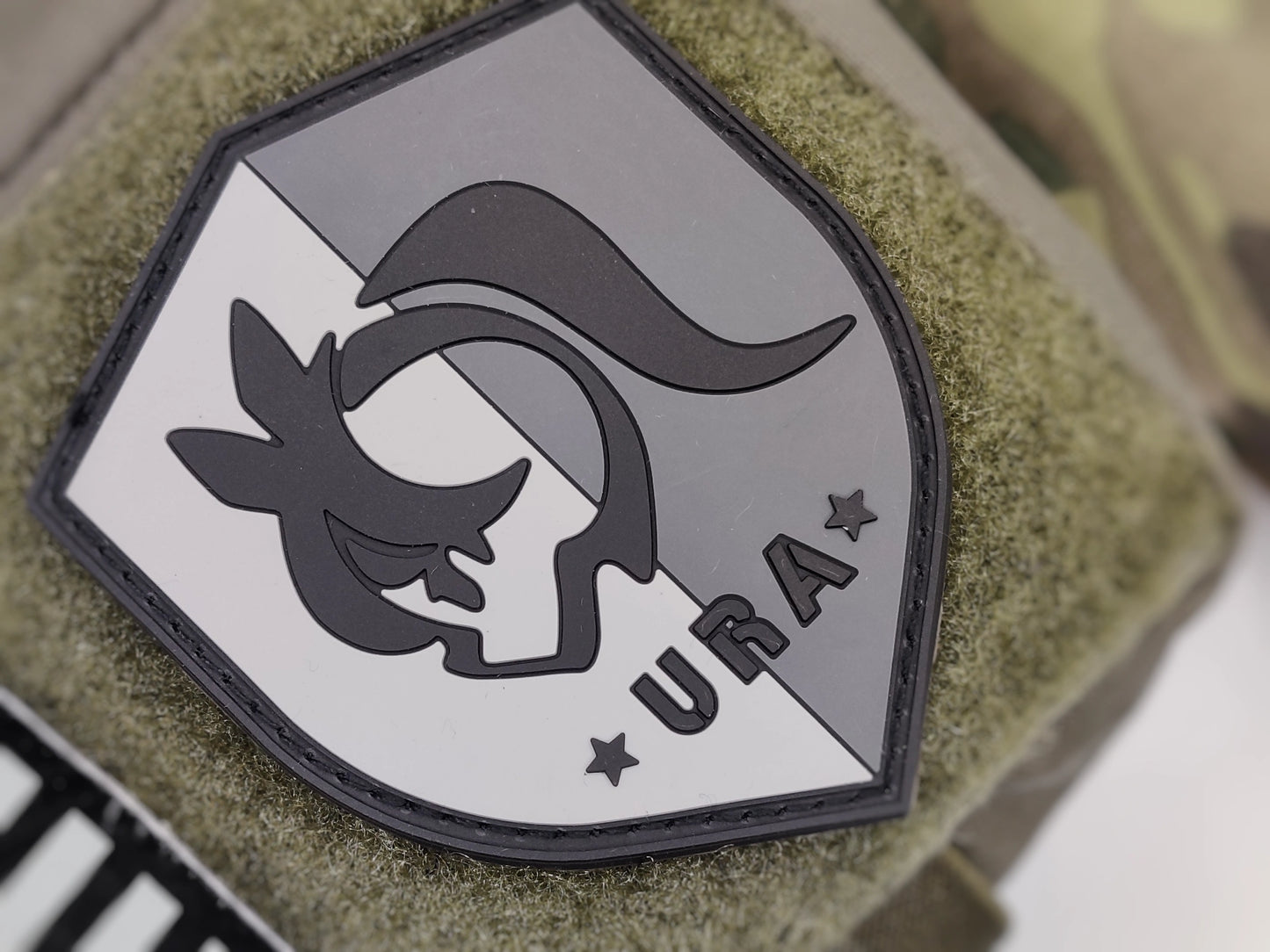 Shield-shaped logo with Umamusume Racing Association emblem and 'URA' text on a green texture background