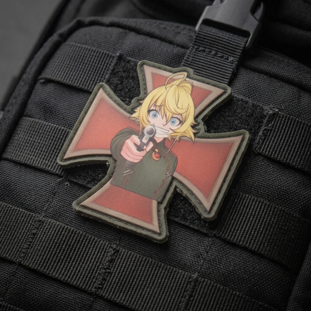 A close-up of a tactical patch featuring an anime-style blonde character in a green uniform pointing a gun, mounted on a black MOLLE webbed bag.