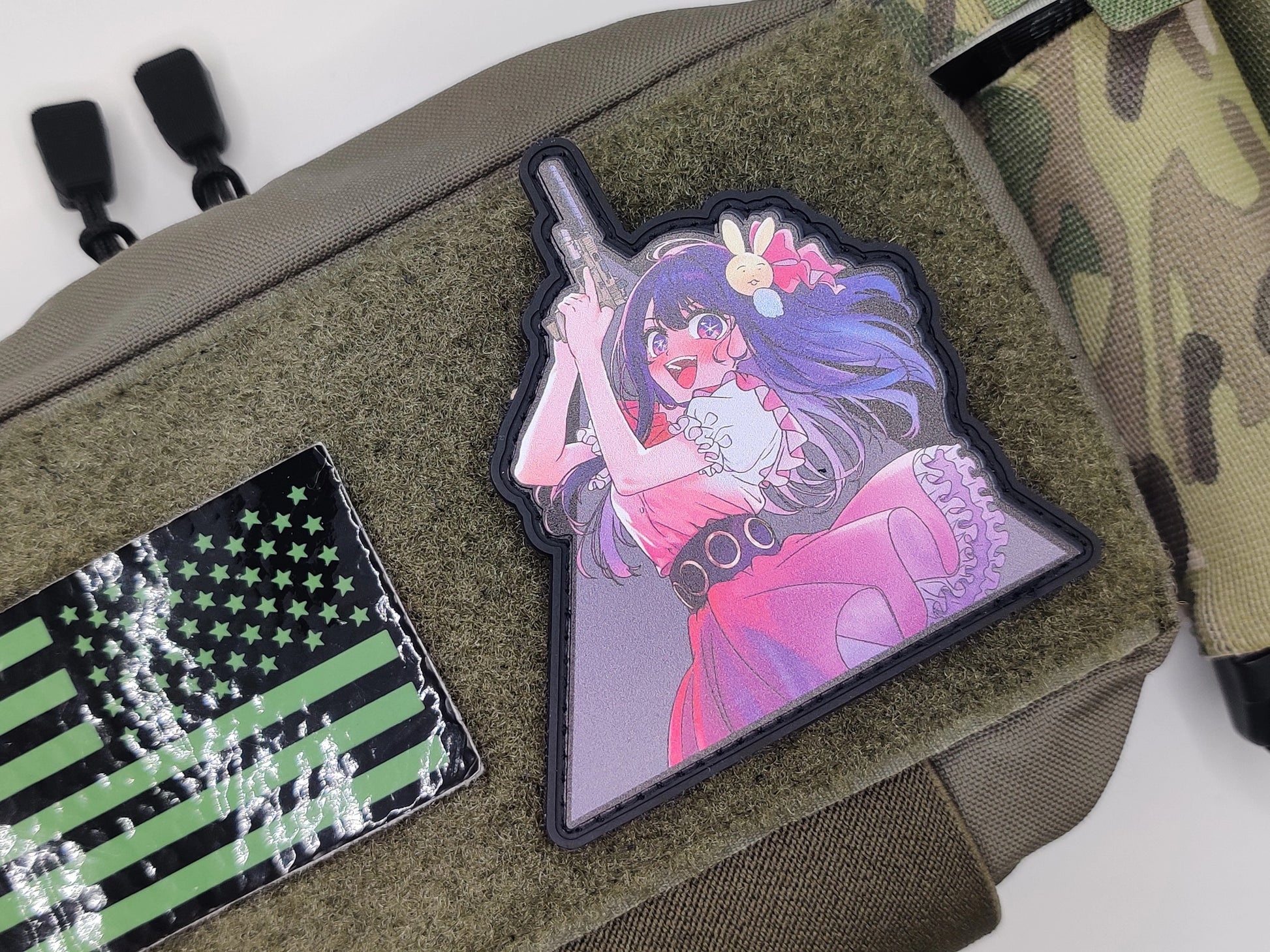 Anime-style character patch on a green bag with a camouflage strap