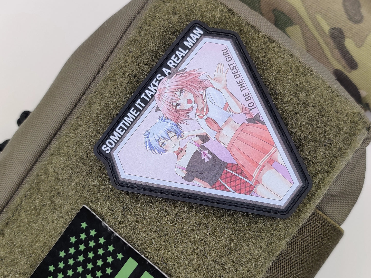 Hexagonal patch with anime-style illustration of Astolfo and Nagisa with the text sometime it takes a real man to be the best girl on a green texture pouch.