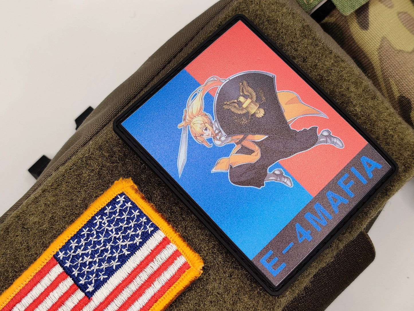 E-4 Mafia Sham Shield Meme Patch on a green surface, one with an American flag design and the other with a colorful graphic and text that says E-4 MAFIA