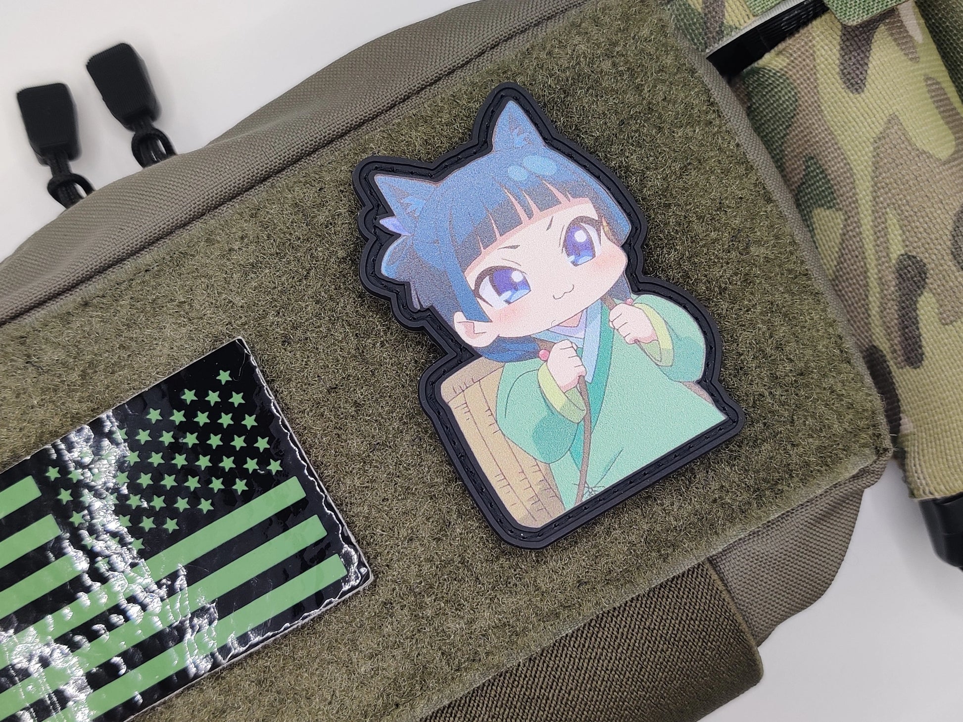 Patch of a character with blue hair and green outfit on a green bag with American flag patch.