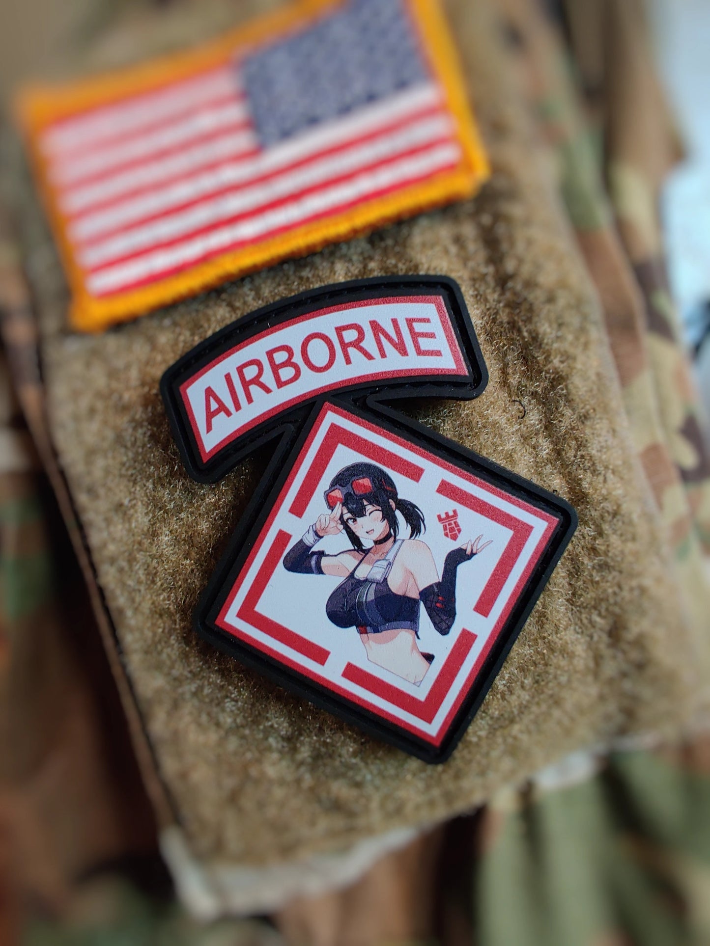Three patches on a camouflage surface: an American flag patch, an 'Airborne' patch, and a character patch.