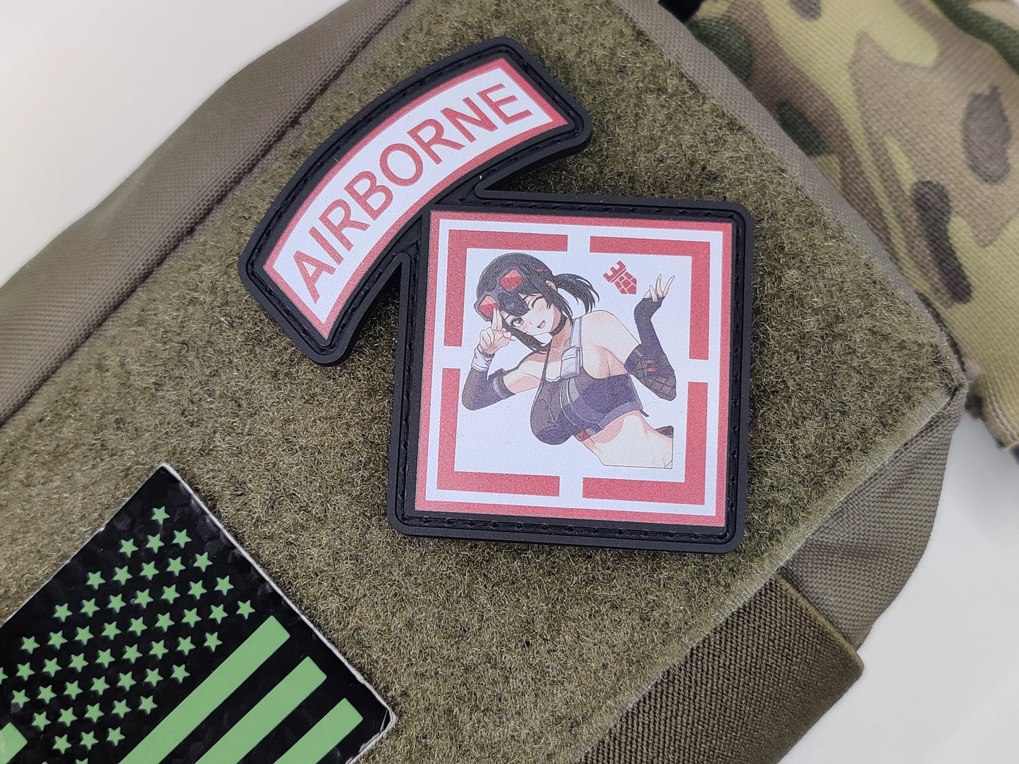 Three patches on a green surface: 'Airborne' patch, cartoon character patch, and American flag patch.