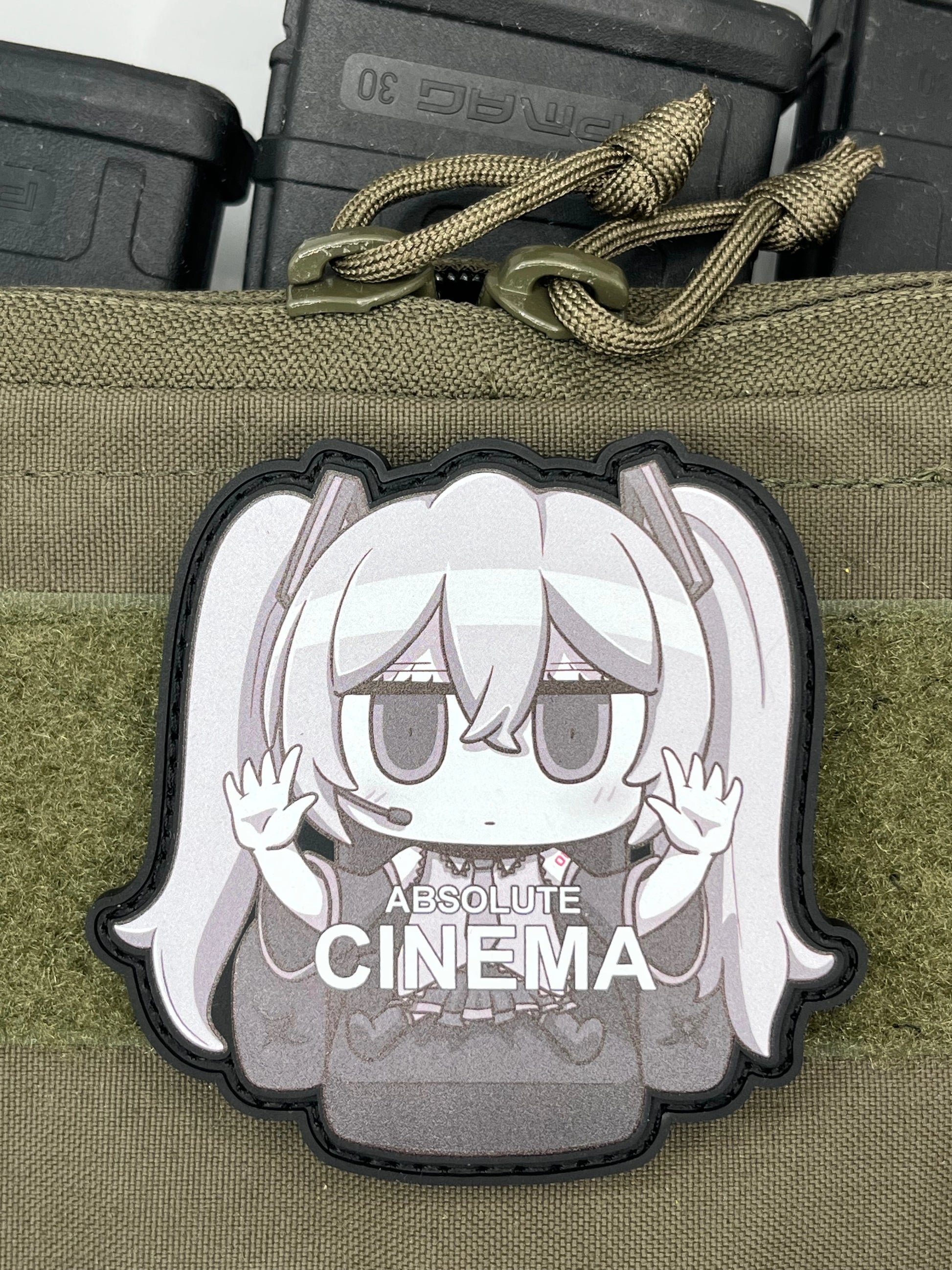 Anime character Hatsune_Miku patch on a green tactical pouch with 'Absolute Cinema' branding.