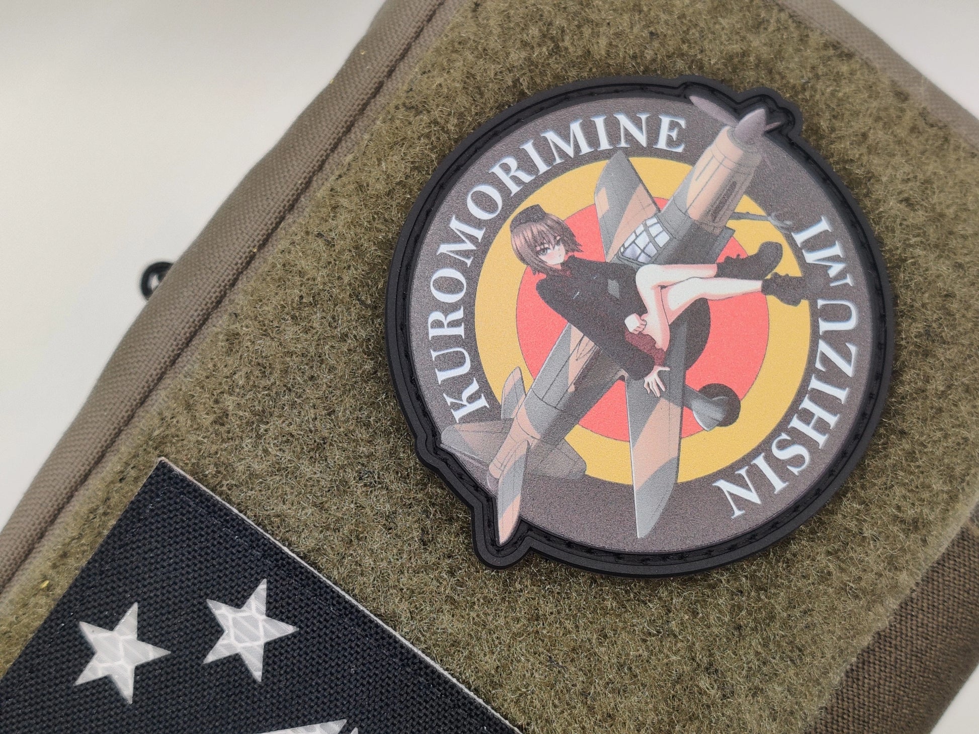 Circular patch with Maho_Nishizumi sitting on a german airplane and text 'Kuromorimine Nishizumi' on a green texture background