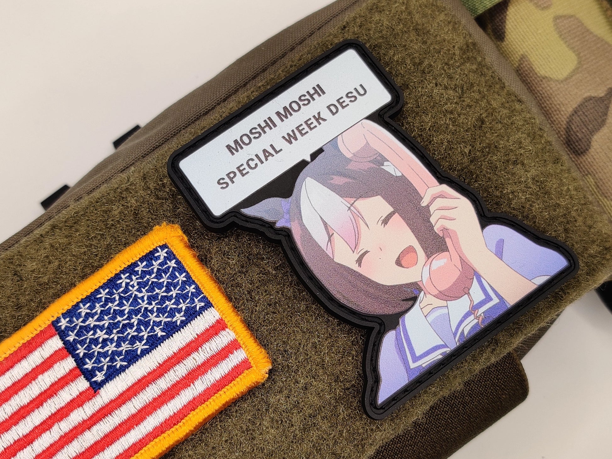 Moshi Moshi Special Week Meme Patch on a green texture background surface. Featuring the character, Special Week with the text MOSHI MOSHI SPECIAL WEEK DESU inside a text bubble