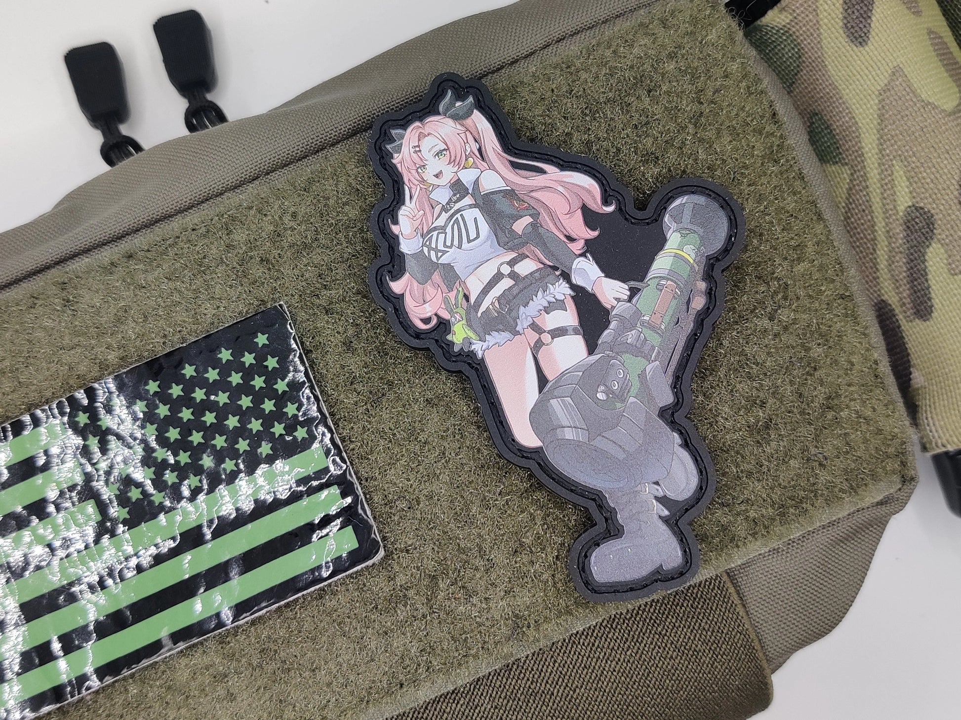 Two patches on a green bag: one with a character design and another with an American flag.