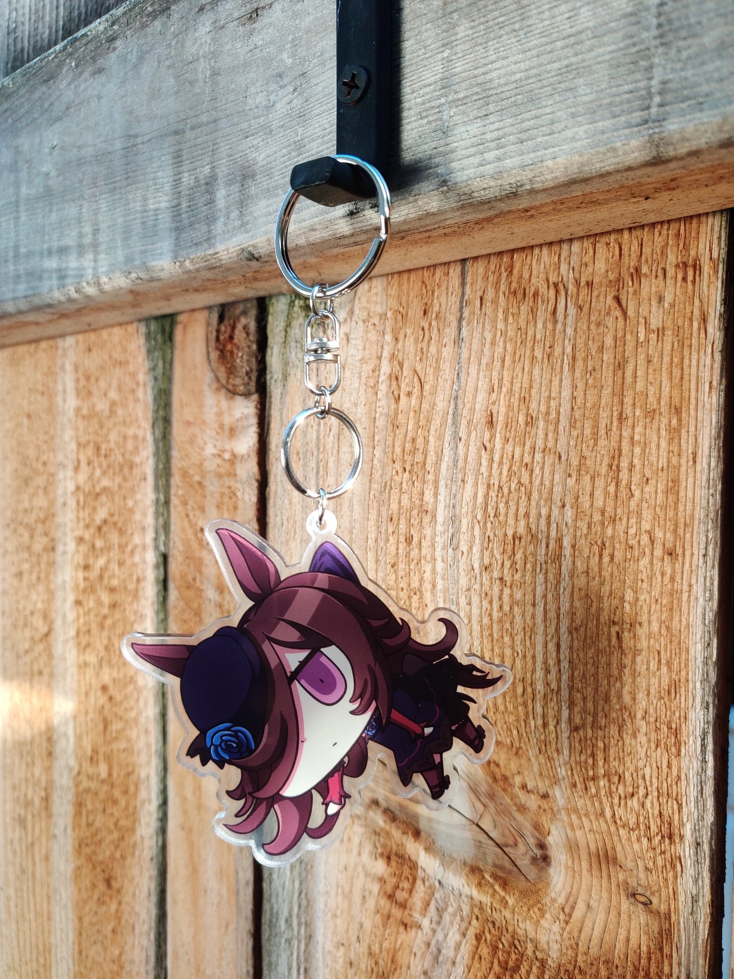 Keychain with rice shower from uma musume hanging on a wooden surface