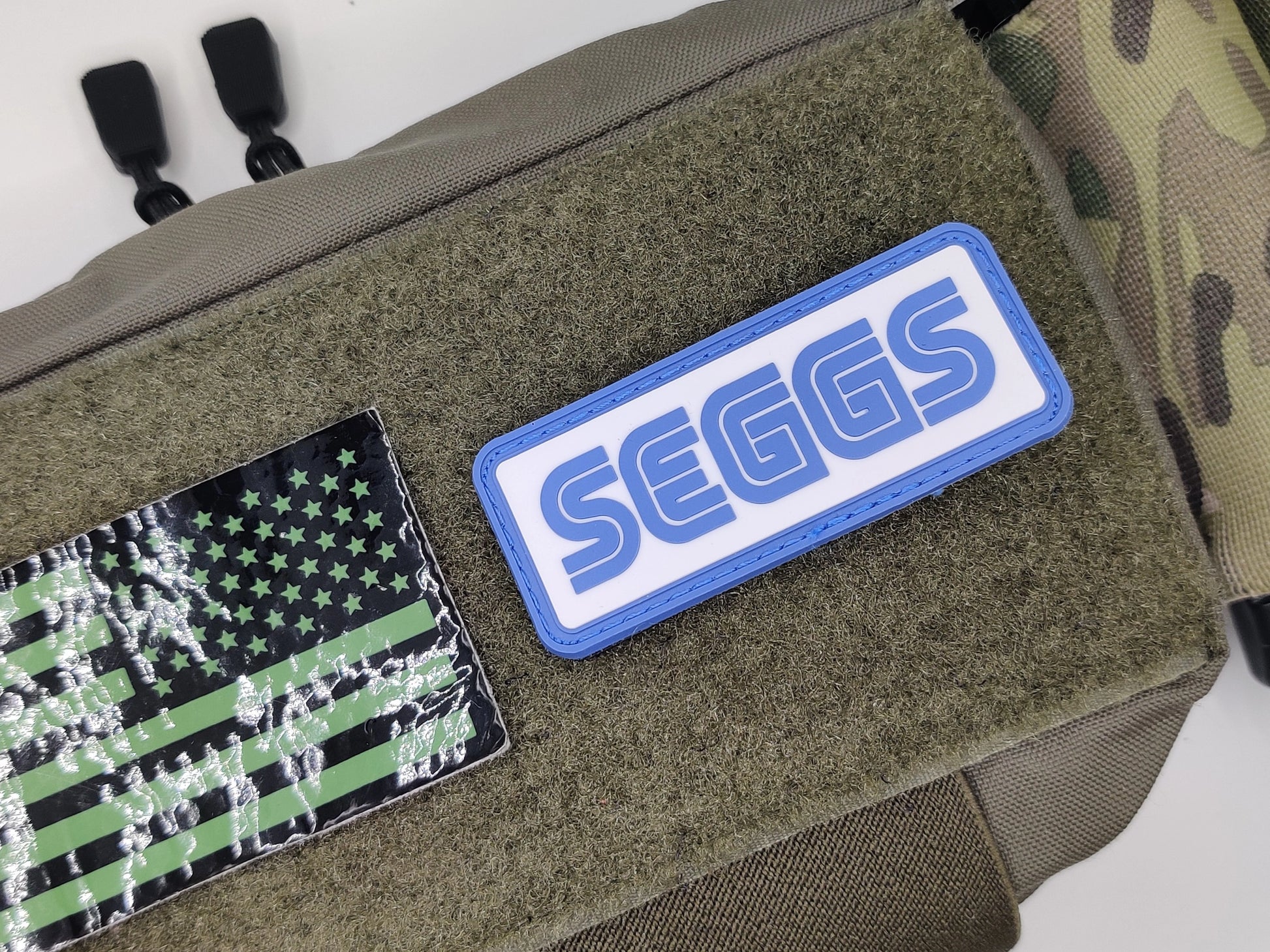 Patches on a green bag, including an American flag patch and a 'SEGGS' patch.