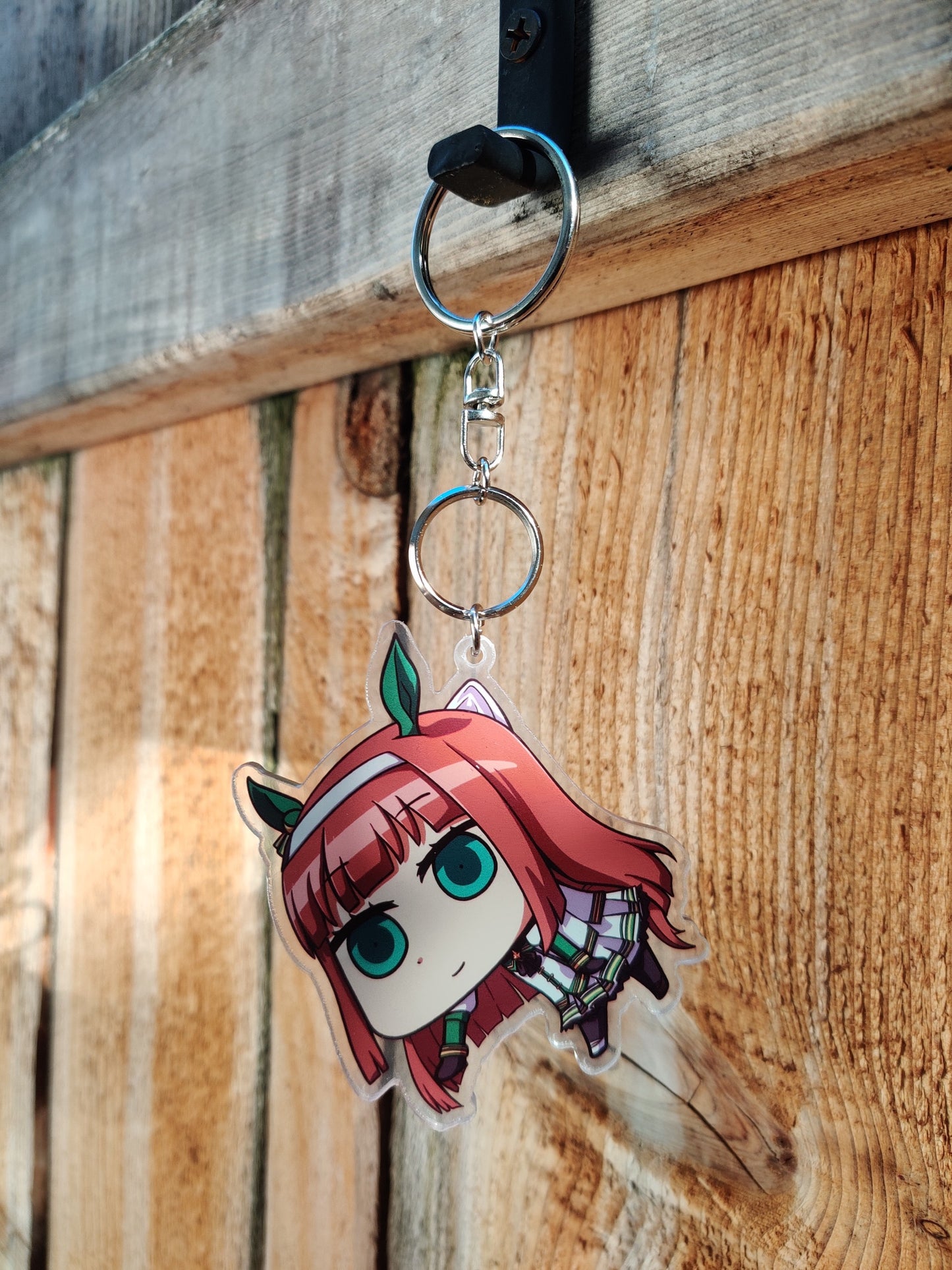 Keychain with anime character silence suzuka from uma musume on a wooden surface