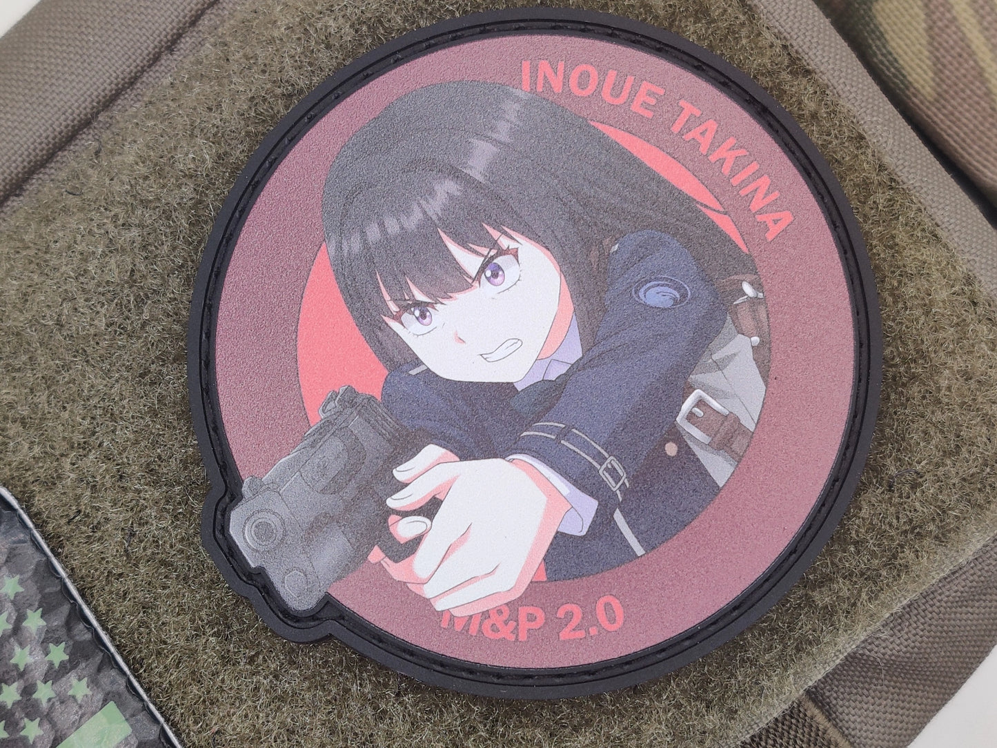 Patch of Takina Inoue from Lycoris Recoil holding a gun with 'Inoue Takina' text on a textured surface