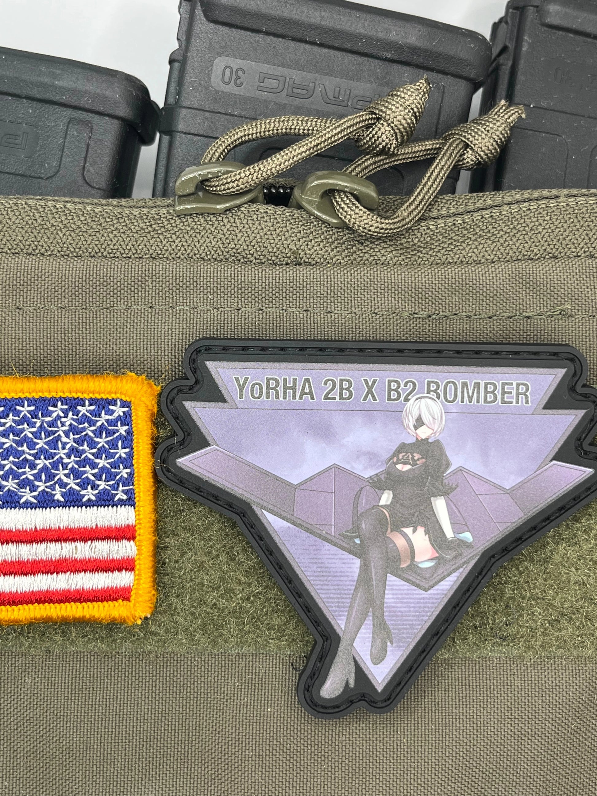Patch of a YoRHa_2B sitting on B2 stealth bomberwith 'Yorha 2B X B2 Bomber' text, American flag patch, and tactical pouch.