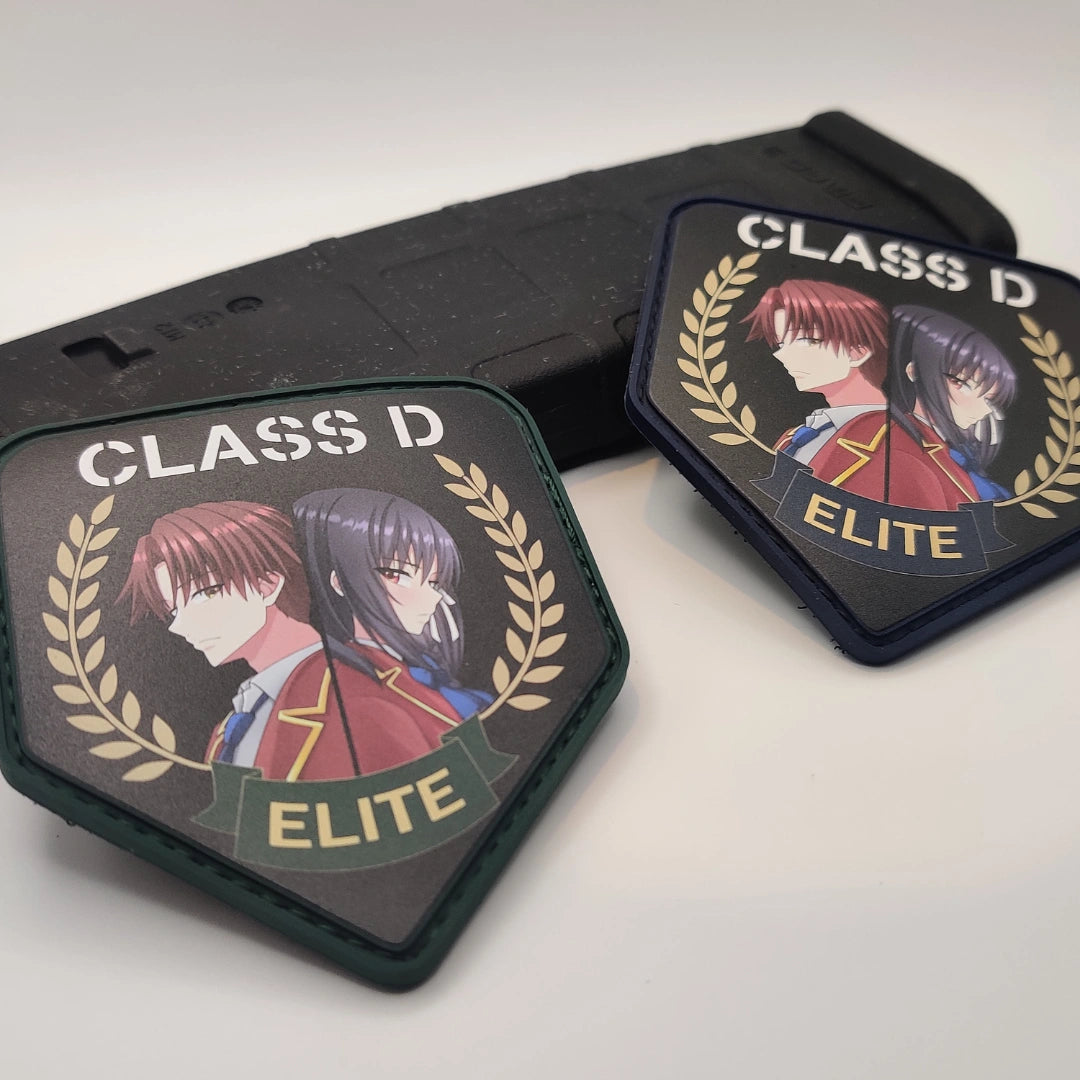 Two Classroom of the Elite Class D patches side by side, green border and navy border versions, resting on a rifle magazine