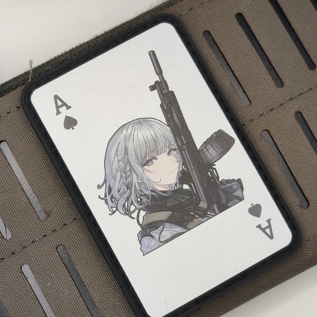 A close-up of a black wallet or card case with a printed playing card design featuring an anime-style character with silver hair holding a rifle, shown inside a brown textured wallet.