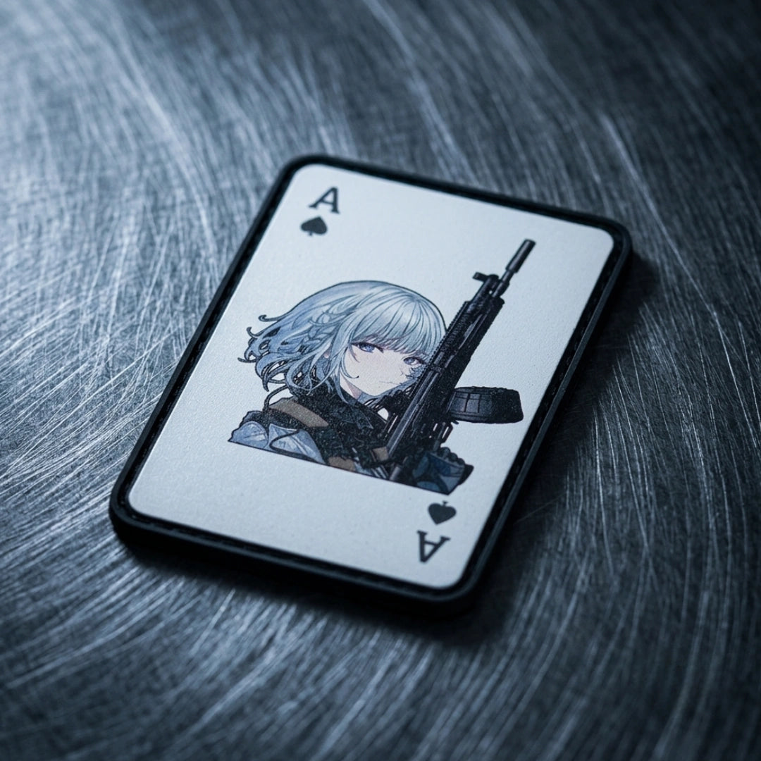 A single playing card with an anime-style illustration of a pale-haired character holding a rifle, photographed on a dark brushed-metal surface.