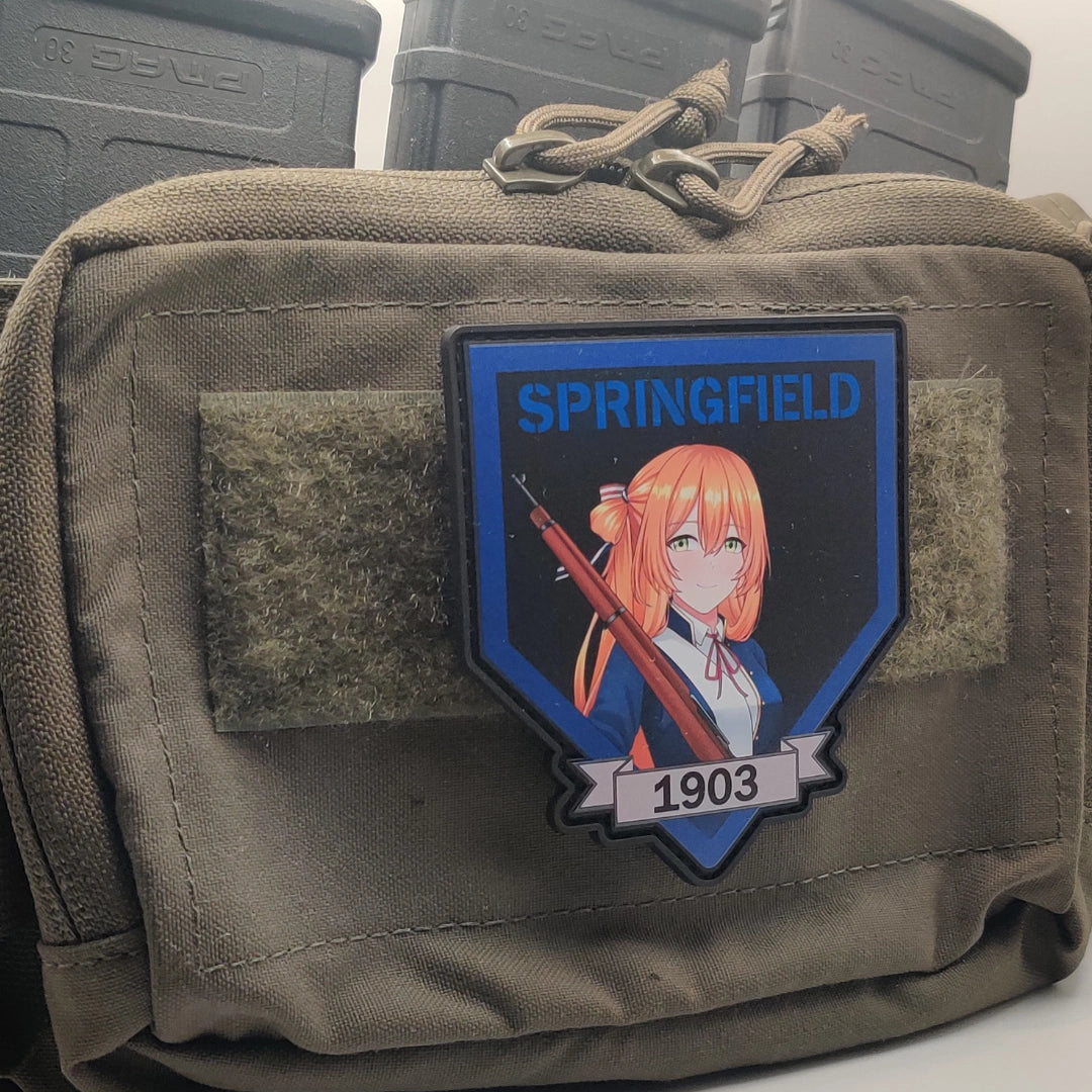 An olive drab tactical pouch featuring a custom PVC patch with an anime character, the word 'SPRINGFIELD', and '1903' on a blue shield background.