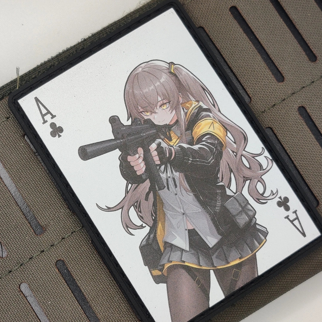 An Ace of Clubs playing card featuring an anime-style female character with long pink hair and a black-and-yellow uniform, resting on a brown textured leather wallet.