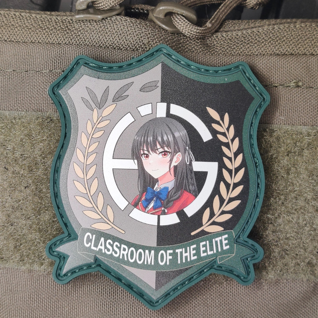 Flat lay of green border Suzune Horikita Classroom of the Elite patch on tan and olive tactical gear with paracord straps visible