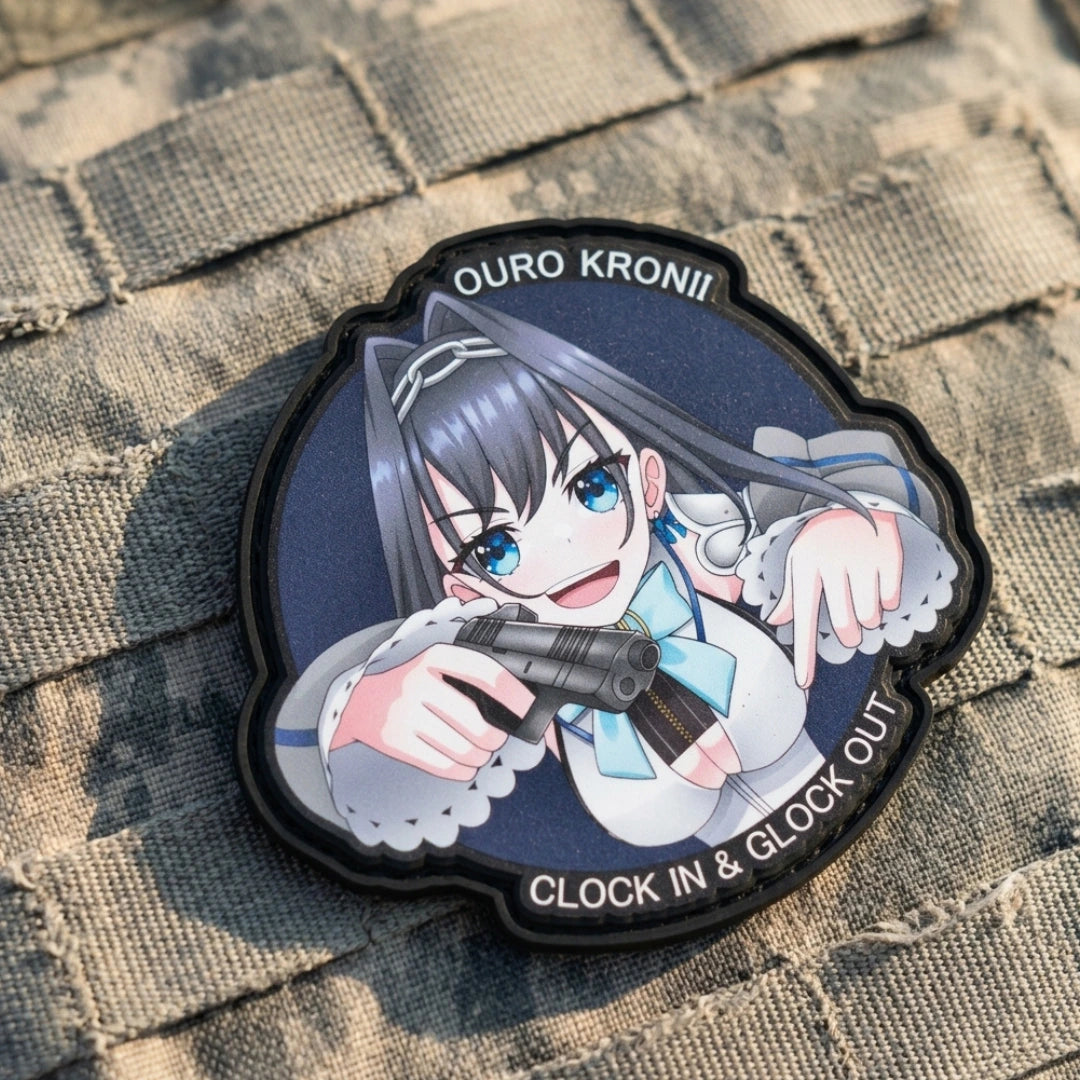 Ouro Kronii "Clock In & Glock Out" patch affixed to camouflage tactical MOLLE webbing with hook-and-loop velcro, showing Hololive Council design on military gear